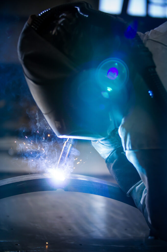 Schweißer bei der Arbeit, Nahaufnahme des Schweißprozesses mit sichtbaren Funken und Schutzmaske